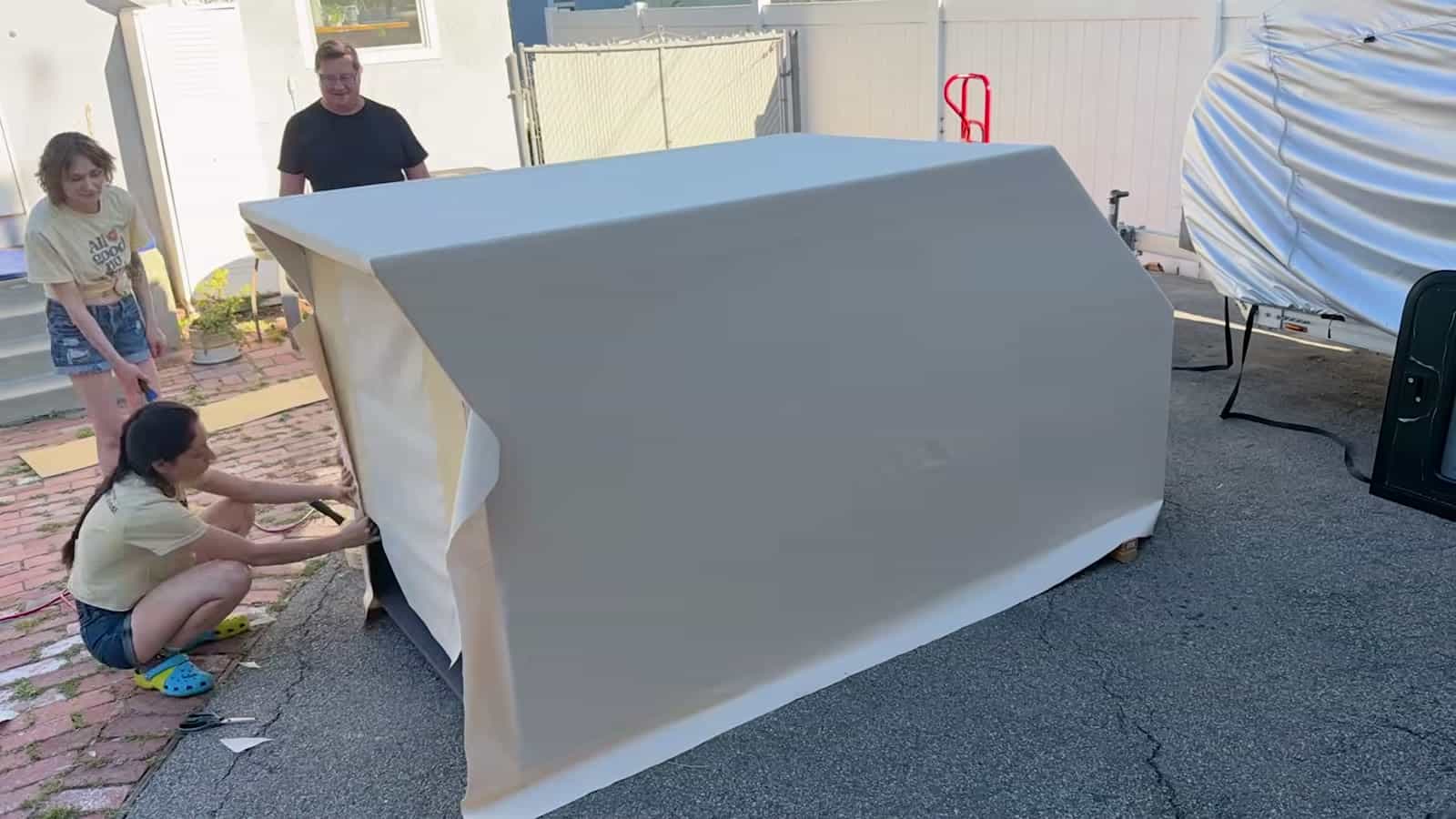 Canvas-wrapped foam camper shell on sawhorses in a driveway