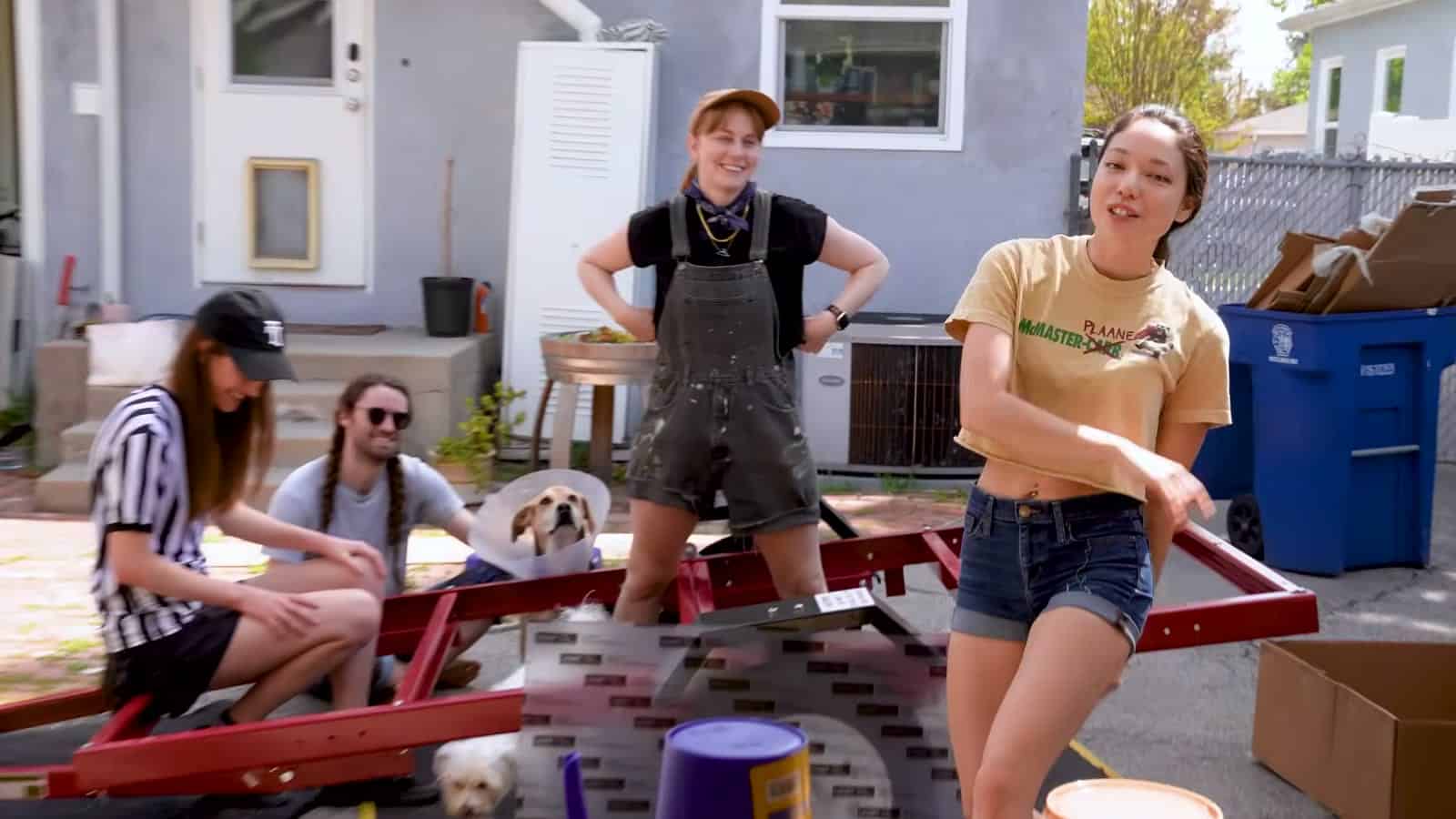 Friends assembling a red Harbor Freight 4x8 utility trailer in a backyard
