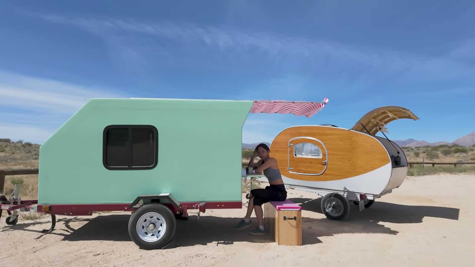 Side view of the foamie teardrop parked beside Xyla Foxlin's first wooden teardrop trailer