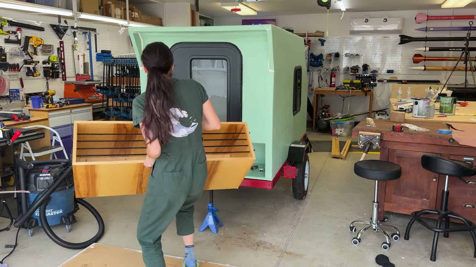 Carrying the plywood tongue box past the finished camper in the shop