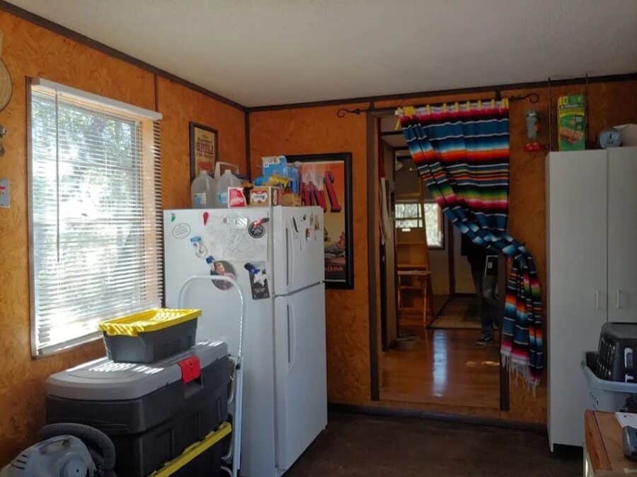 Interior view of a compact kitchen in a tiny house with a refrigerator, microwave, and colorful curt.