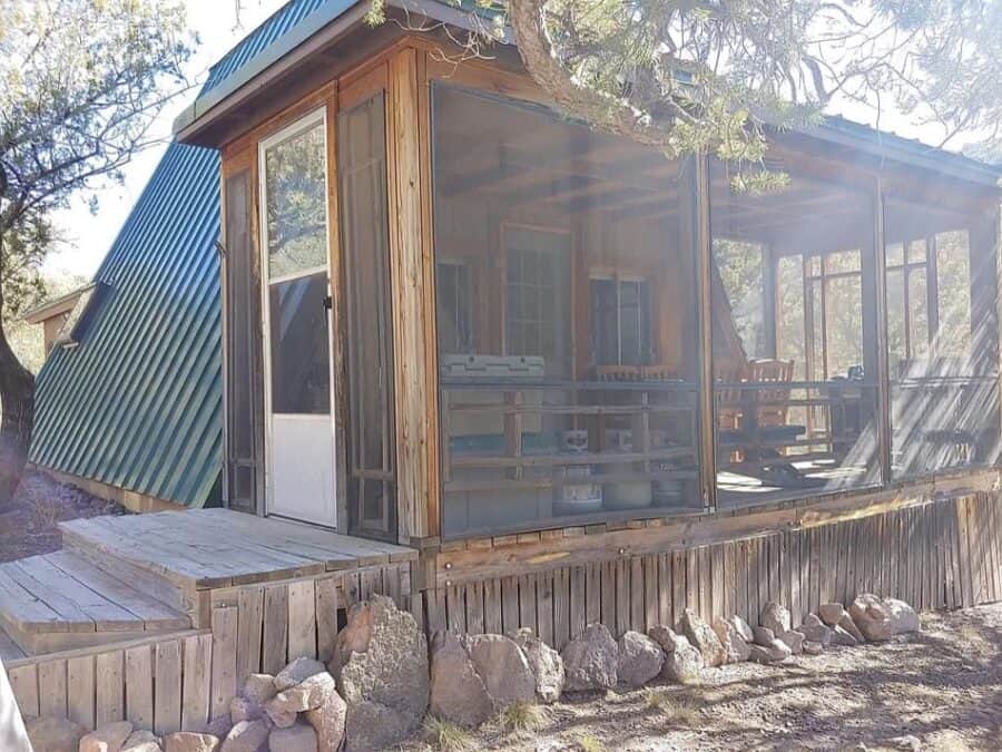 A-frame tiny house with wooden exterior and screened porch in Fort Davis, Texas.