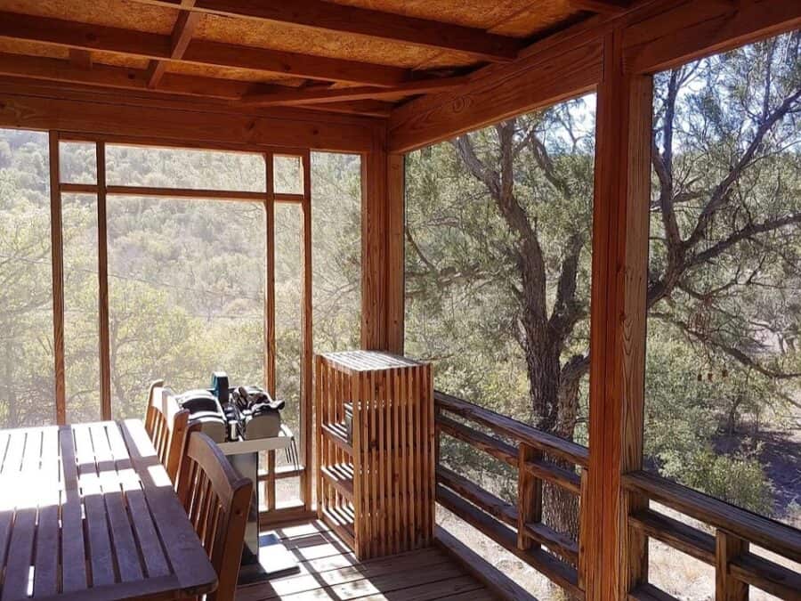 Porch of a tiny house overlooking trees and natural landscape in Fort Davis, Texas.
