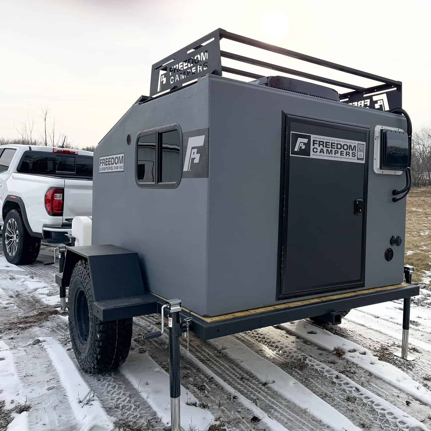 Front corner of a 72 x 89 Freedom Camper trailer showing the door and window