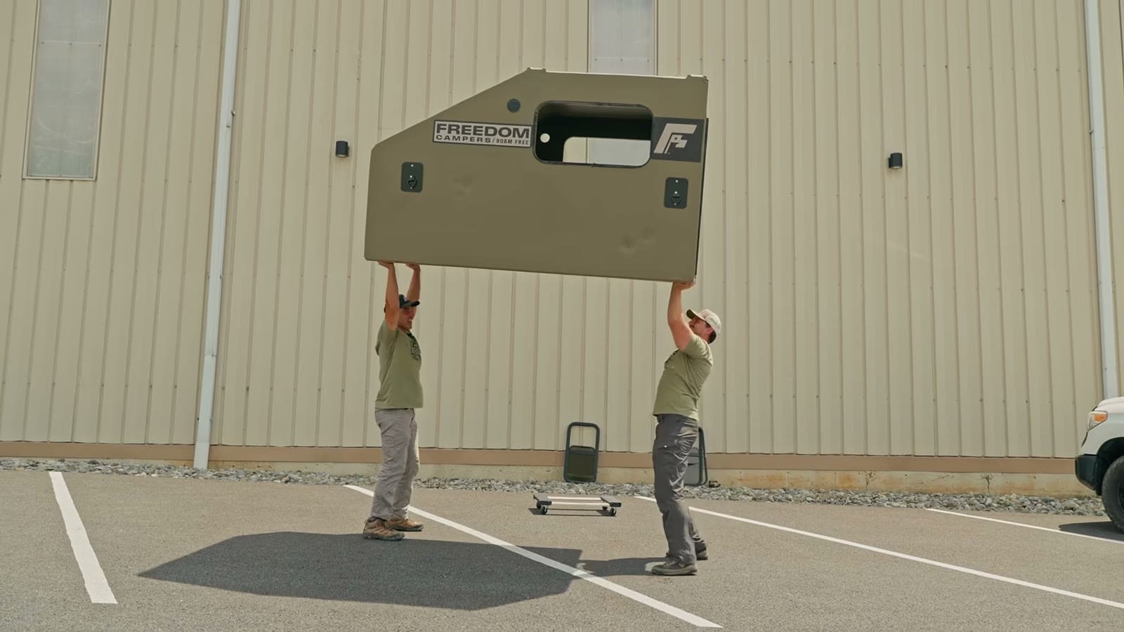 Two people lifting a Freedom Camper shell overhead