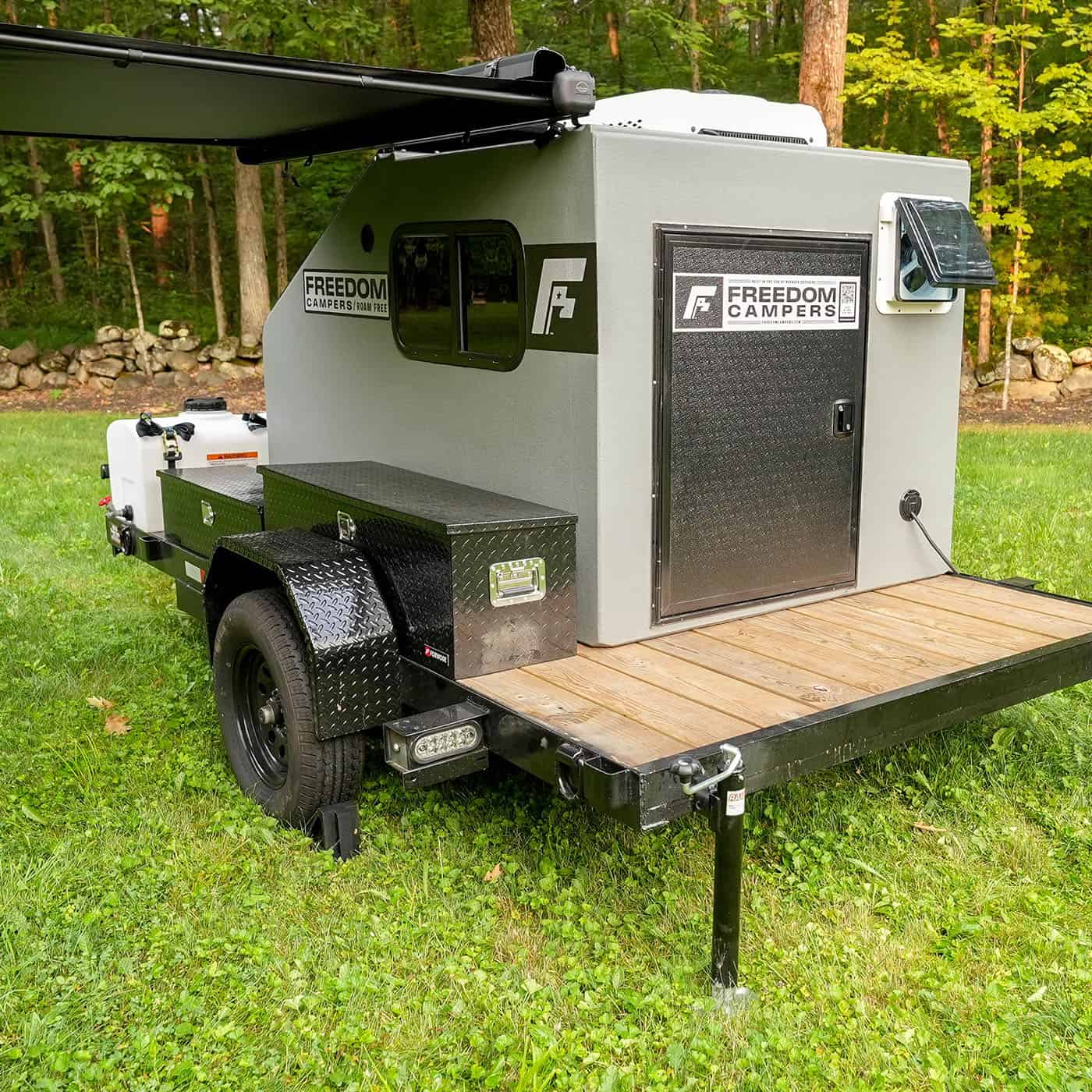 Freedom Camper trailer with a wood rear deck, toolbox, and roll-out awning