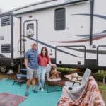 Beautiful couple with their dog in front of a modern 5th wheel RV.