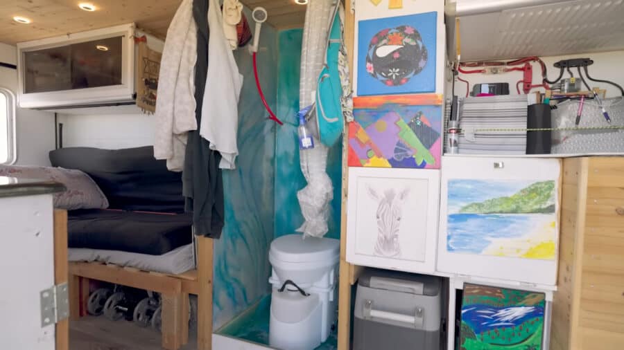 Cozy tiny house interior featuring organized storage, artwork, and a small bathroom area.