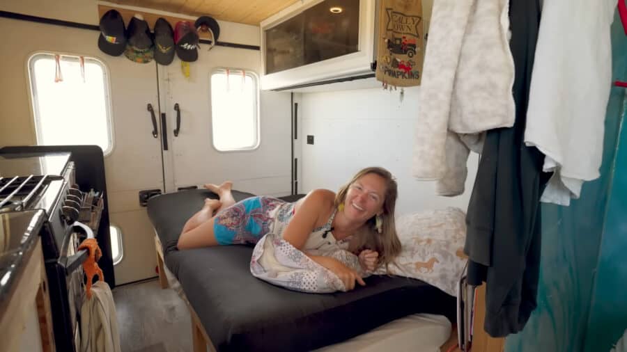 Compact tiny house interior with a woman lying on a bed, showcasing efficient use of space and cozy.