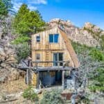 Small wooden tiny house nestled among trees with mountain backdrop in Arizona.