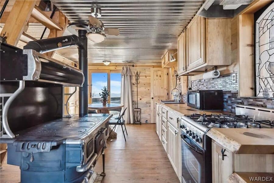 Interior of a tiny cabin kitchen with wood accents and mountain view through the window.