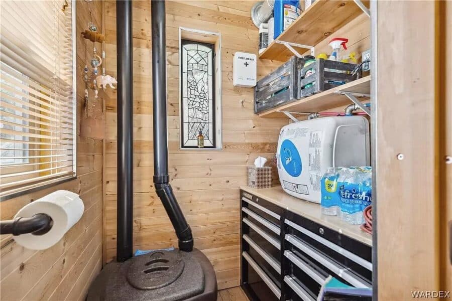 Compact tiny house storage area with wood interior and mountain scenery in the background.