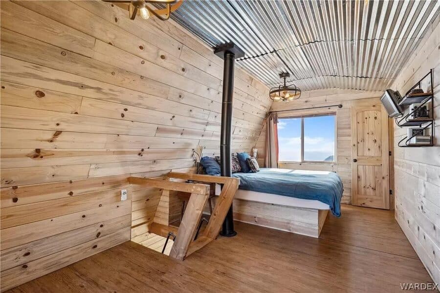 Charming tiny cabin interior featuring wooden walls and a comfortable bed with mountain scenery outs.