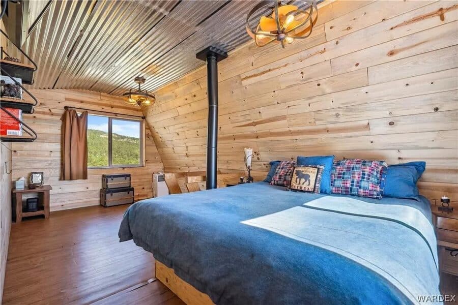 Interior of a tiny cabin bedroom with mountain views, wooden walls, and cozy decor.
