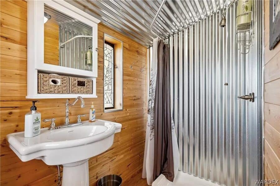Bathroom in a tiny house with wooden walls and a metal shower stall.