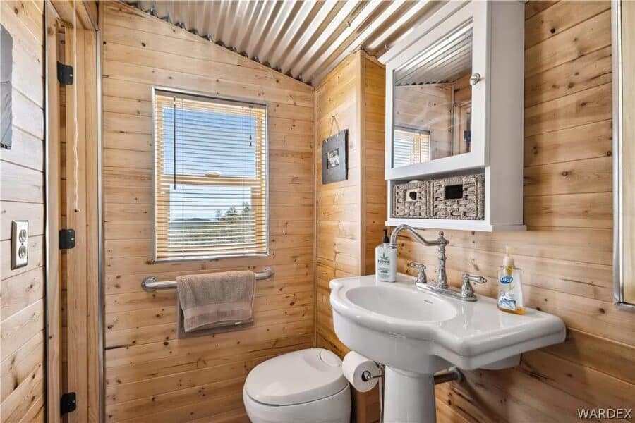 Charming rustic bathroom inside an Arizona cabin featuring wood-paneled walls and mountain scenery o.