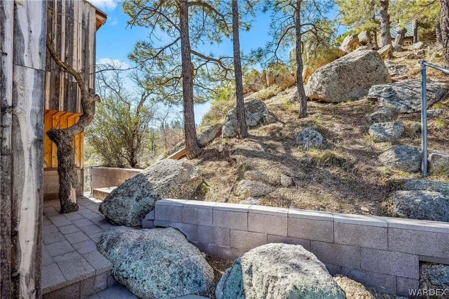 Arizona cabin nestled among rocks and trees with mountain scenery in the background.