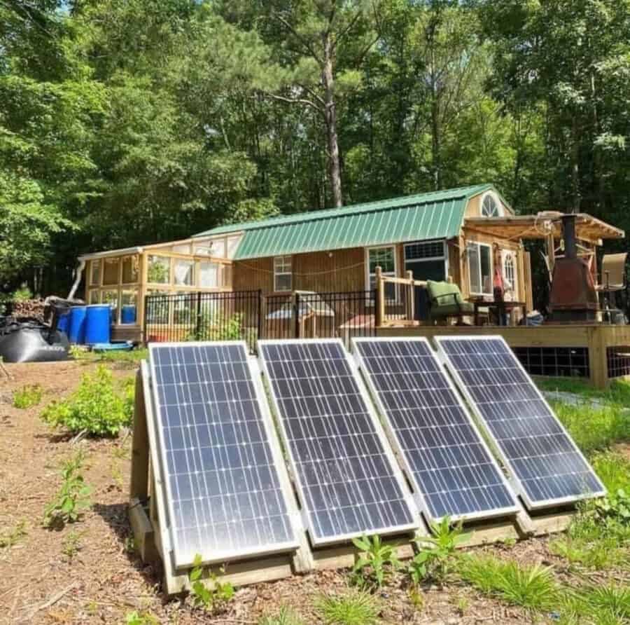 Eco-friendly tiny house with solar panels and green surroundings for sustainable living.