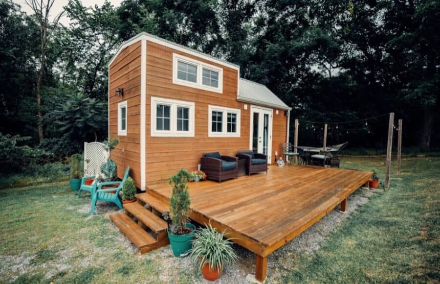 Modern tiny house with large outdoor deck and cozy seating area.
