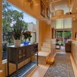 Charming tiny house interior with natural wood finishes, large windows, and modern amenities in Esca.
