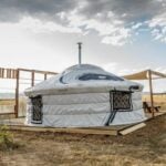 Yurt in open landscape with wooden deck and sky view.