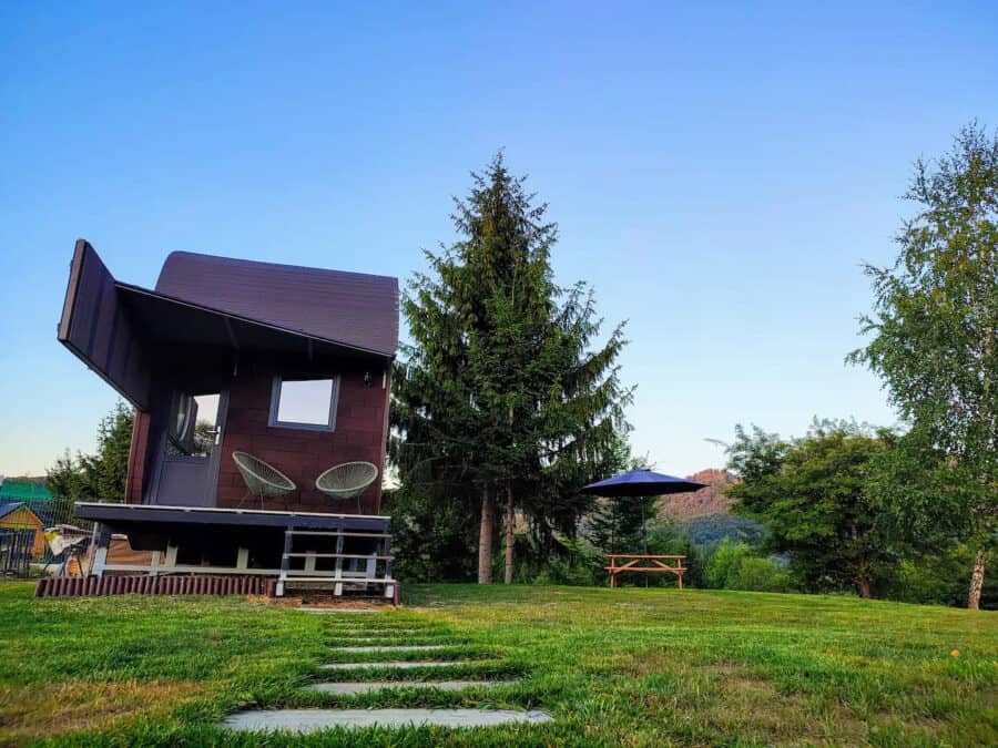 Unique guitar-shaped tiny house in Romania with scenic mountain views and lush greenery.
