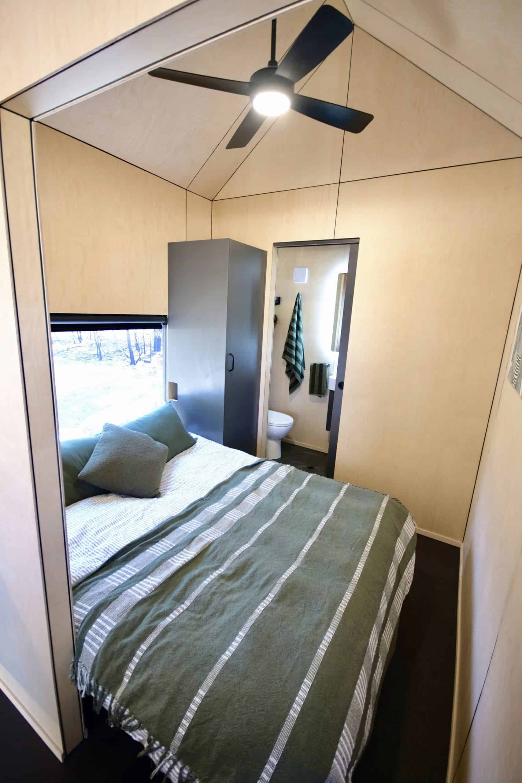 Ground-floor queen bedroom in the Eire tiny house with wardrobe and window
