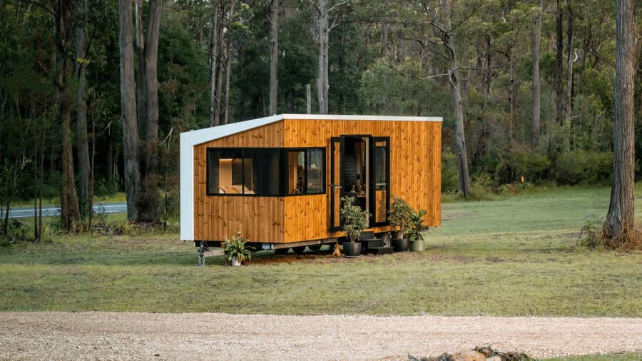 Modern Luna tiny house on wheels with wooden exterior in a natural setting, showcasing small space l.