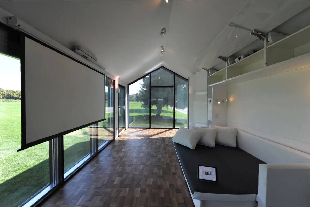 Cozy tiny house living room with expansive glass windows and scenic outdoor views.
