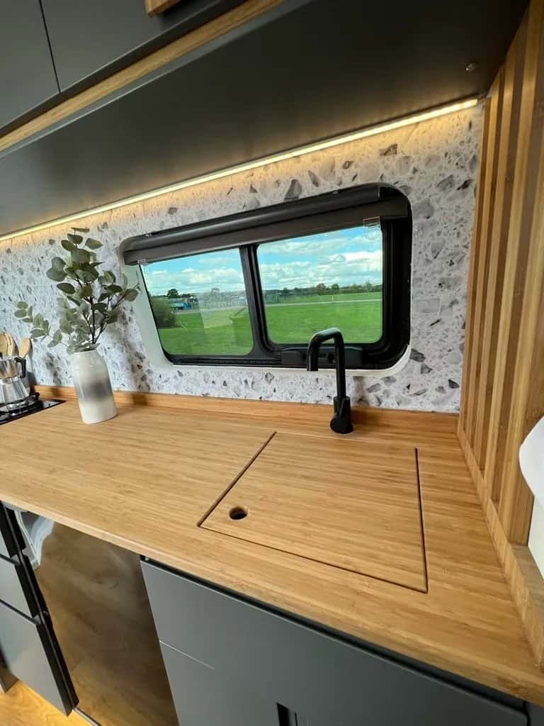 Compact kitchen featuring a large window and wooden countertop for small space living.