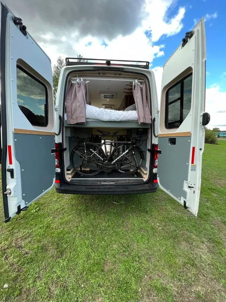 Van life tiny home with a cozy bed and secure bicycle storage area. Perfect for small space living a.
