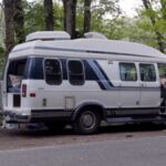 Retro van parked in forest, perfect for tiny house living on wheels.