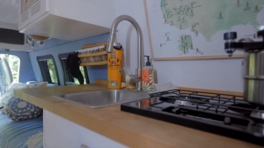 Compact kitchen with sink and stove in a retro van conversion.