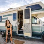 Woman enjoying her tiny camper van in open landscape.
