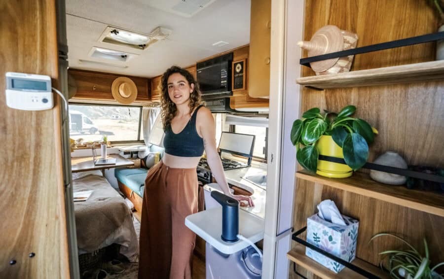 Woman enjoying her cozy camper interior with wooden accents and modern amenities.