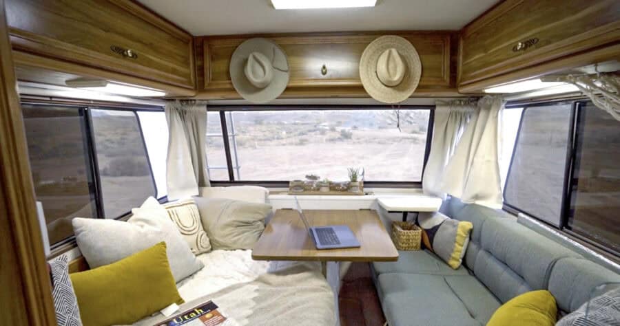 Interior of a Lazy Daze camper with cozy seating and large windows.