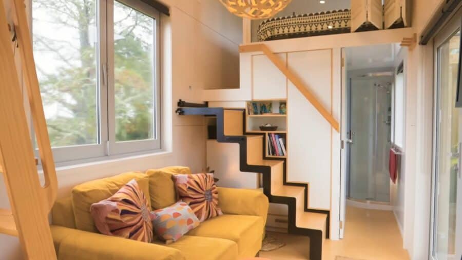 Bright tiny house interior with a yellow sofa and colorful pillows.
