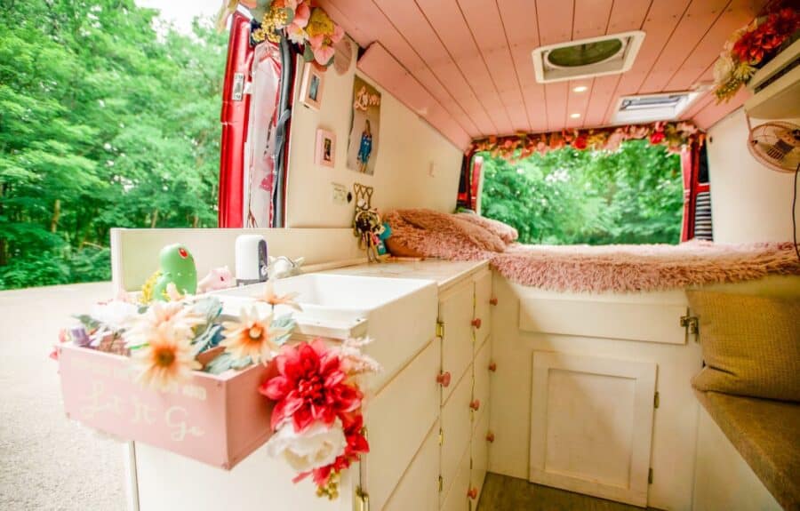 Interior of a cozy van with floral decorations and a bed, inspired by Taylor Swift's style.