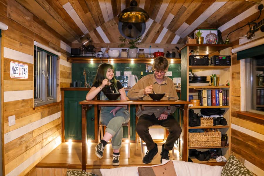 Charming tiny house interior featuring a young couple enjoying a meal at a wooden table in a compact.