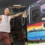 Compact truck camper tiny home with vibrant mountain and lake mural.