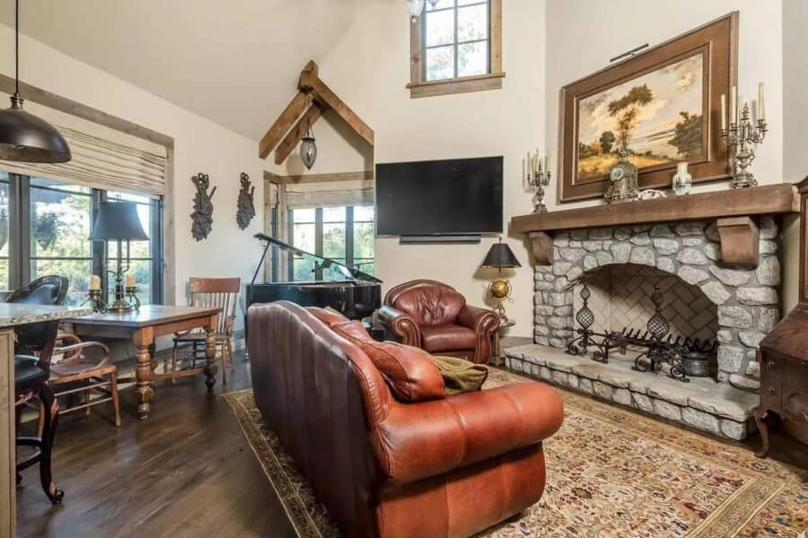 Warm living room featuring a stone fireplace, leather sofas, and rustic decor in a tiny house.