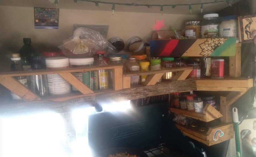Organized tiny house storage with shelves holding jars and supplies.