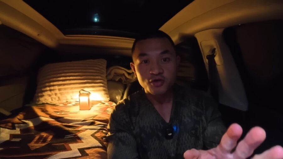 Tesla stealth camper van at night with cozy sleeping area inside.