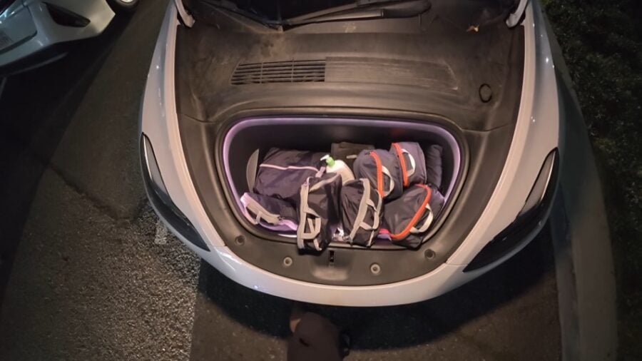 Tesla car trunk with backpacks, converted into a stealth camper for nomadic living.