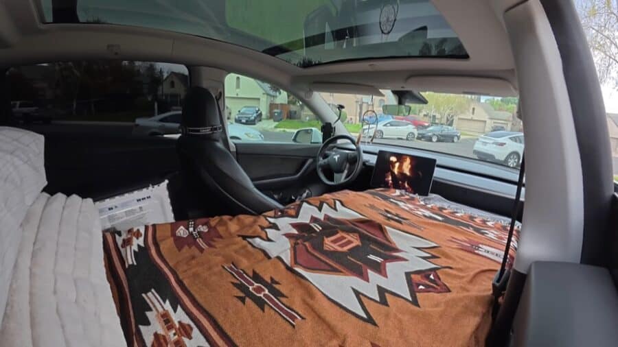 Tesla stealth camper interior with cozy bed setup.