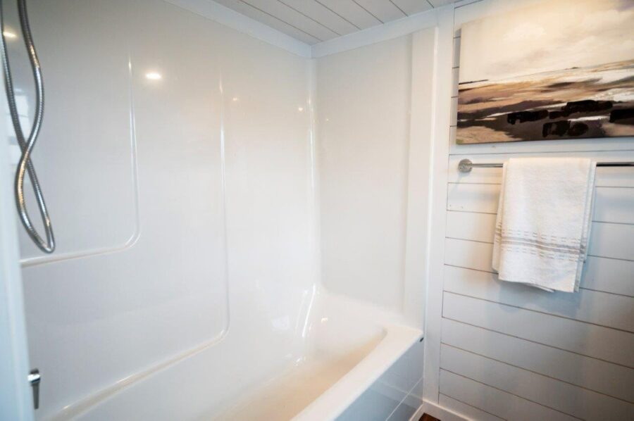 Modern tiny house bathroom with white tub and shiplap walls.