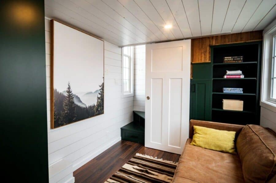 Interior view of a modern tiny house with white walls, wooden accents, and a comfortable sofa.