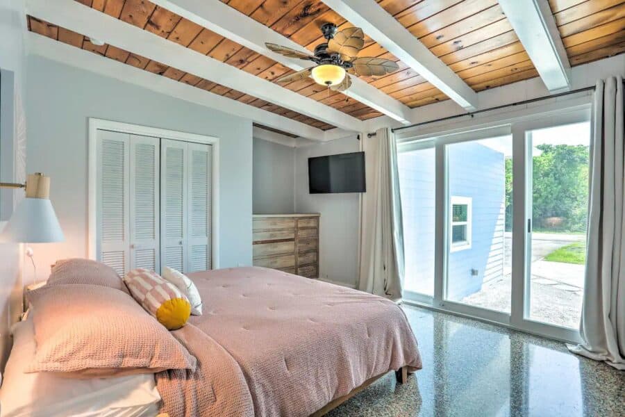 Charming tiny house bedroom featuring a wooden ceiling, large windows, and modern decor for small sp.