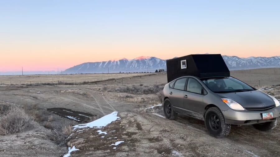 Prius converted into a compact overlander vehicle in a rugged landscape.