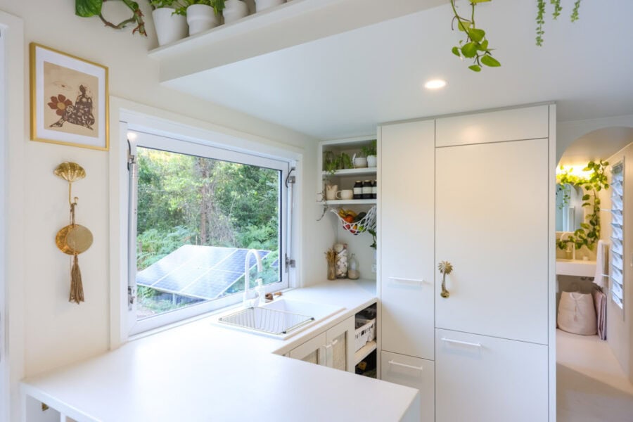 Bright tiny house kitchen with large window and minimalist design.